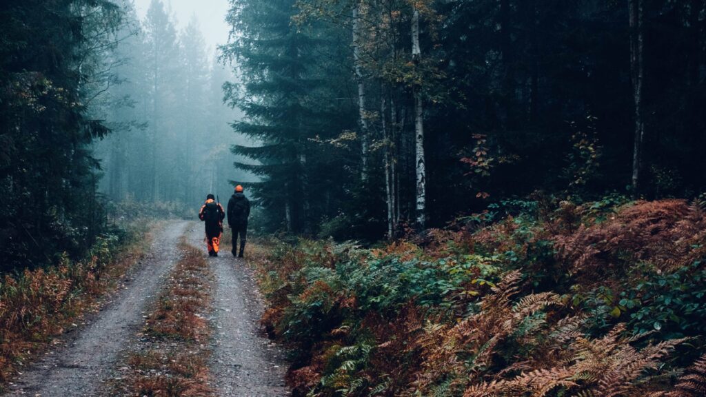 En man och en kvinna gående i skogen under jaktsäsong.